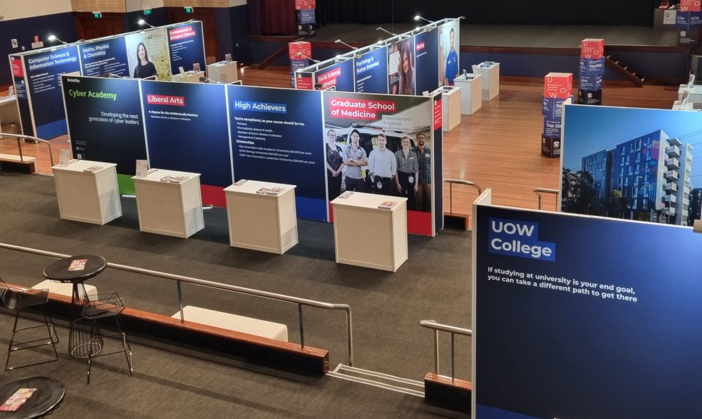 Overhead photo of University open day with exhibition pods for each faculty. Exhibition system with counters and large format digital printed fabric graphics.